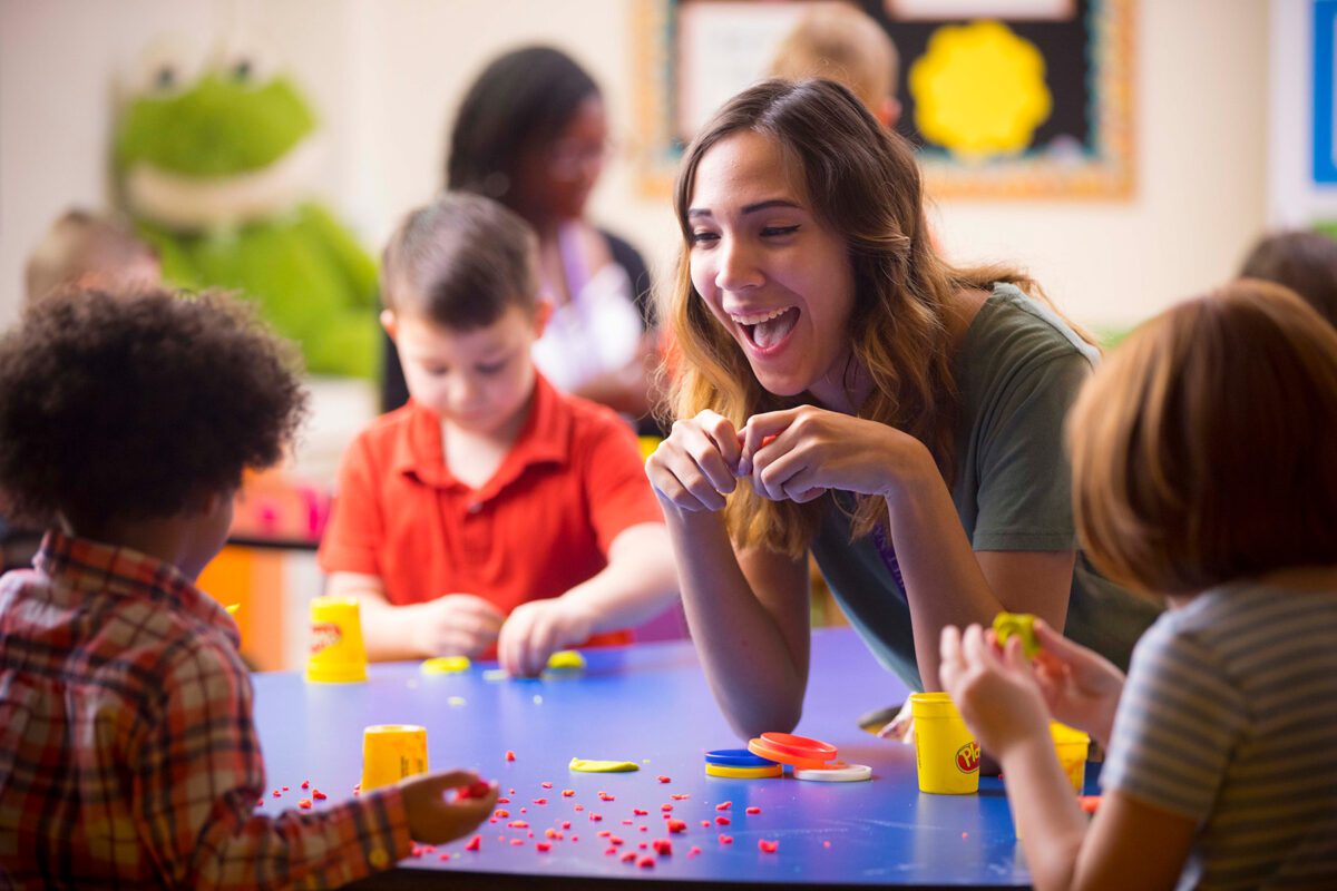 girl smiling and playing playdough