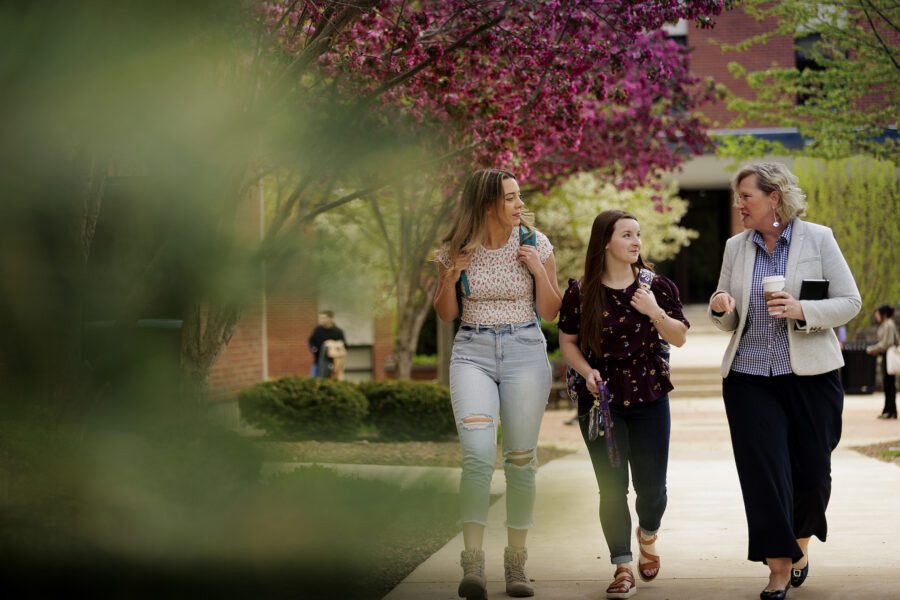 Susan Wolff walking and talking to students on campus