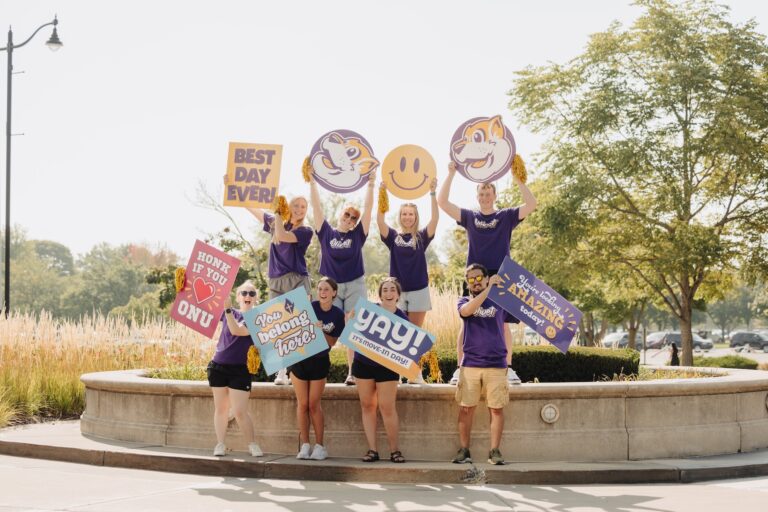 students smiling and holding signs