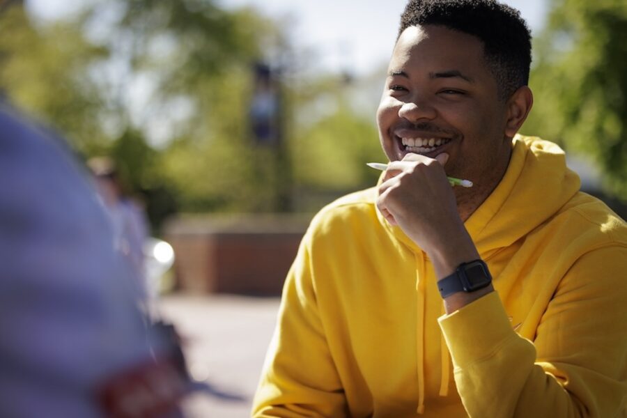 male student holding a pencil and smiling